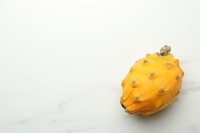 Photo of Delicious yellow pitahaya fruit on white marble table, top view. Space for text
