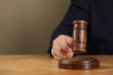 Man with gavel at wooden table, closeup. Space for text