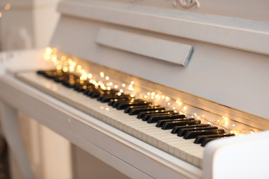 Glowing fairy lights on piano keys, closeup. Christmas music