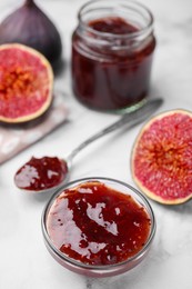 Photo of Tasty sweet fig jam and fruits on white marble table