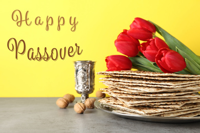 Passover matzos, goblet, walnuts and tulips on grey table. Pesach celebration