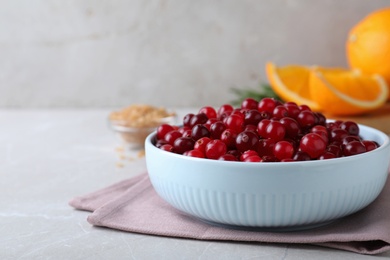 Fresh ripe cranberries in bowl on light table. Space for text