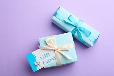 Gift card and presents on violet background, flat lay