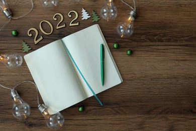 Open planner and Christmas decor on wooden background, flat lay. 2022 New Year aims