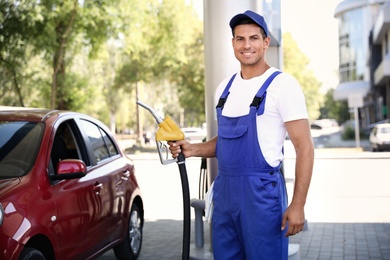Worker with fuel pump nozzle at gas station