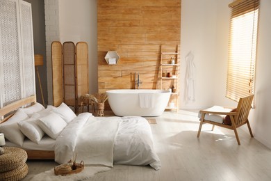 Stylish apartment interior with white bathtub and bed