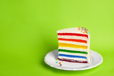 Slice of delicious rainbow cake on color background