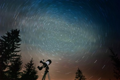 Modern telescope under night sky with star trails outdoors, low angle view. Learning astronomy