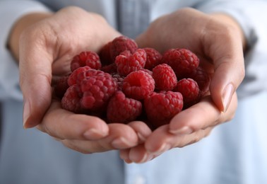 Woman holding red fresh ripe raspberries, closeup
