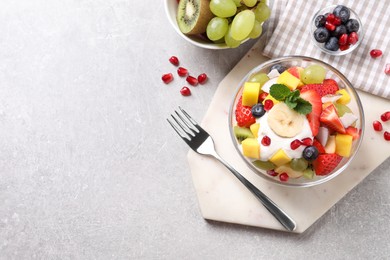 Delicious fruit salad on light grey table, flat lay. Space for text