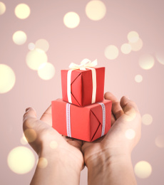 Boxing day. Woman with gifts on beige background, closeup