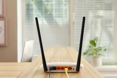 Modern wi-fi router on wooden counter indoors