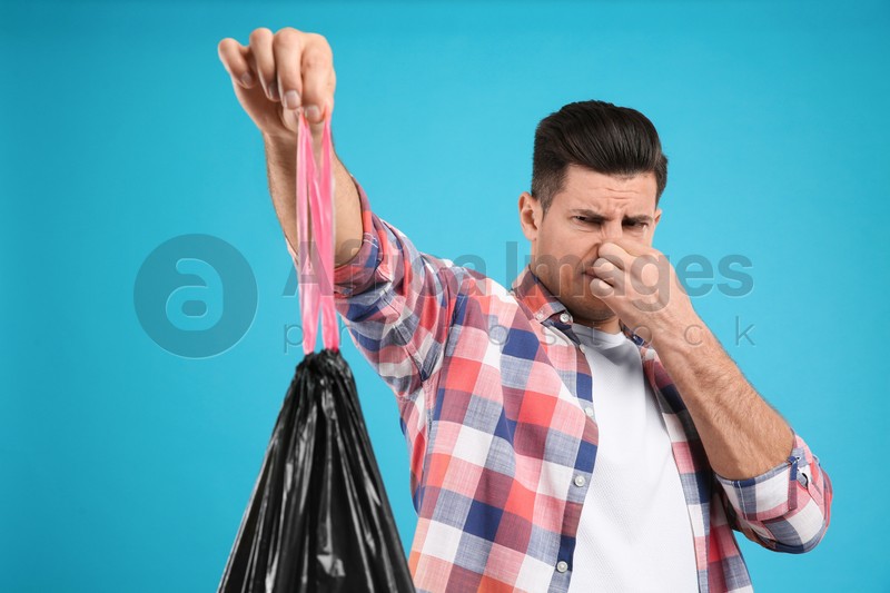 Man holding full garbage bag on light blue background