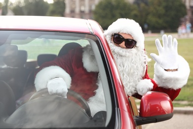 Authentic Santa Claus with sunglasses driving car, view from outside