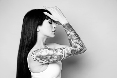 Beautiful woman with tattoos on light background. Black and white photography