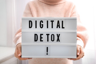 Photo of Woman holding lightbox with phrase DIGITAL DETOX at home, closeup