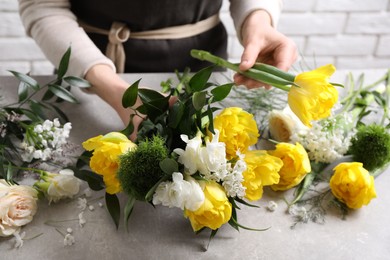 Florist making beautiful bouquet at grey table, closeup