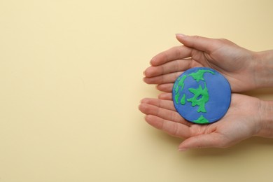 Woman holding model of planet on beige background, top view with space for text. Earth Day