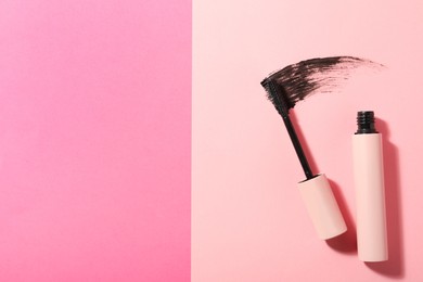 Mascara and smear on pink background, flat lay with space for text. Makeup product