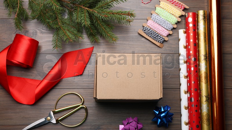 Box, wrapping paper and scissors on wooden table, flat lay