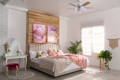 Stylish room interior with large comfortable bed and beautiful paintings