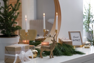 Decorative reindeer near gift box on shelf with Christmas decor. Interior design