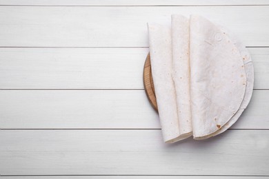 Photo of Delicious folded Armenian lavash on white wooden table, top view. Space for text