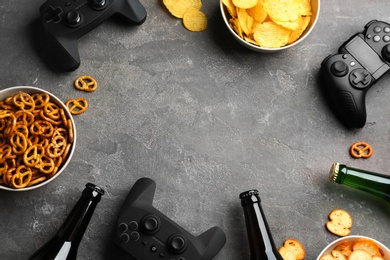 Flat lay composition with video game controllers, snacks and space for text on grey background