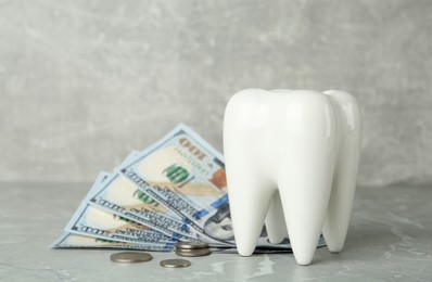 Ceramic model of tooth and money on grey table. Expensive treatment