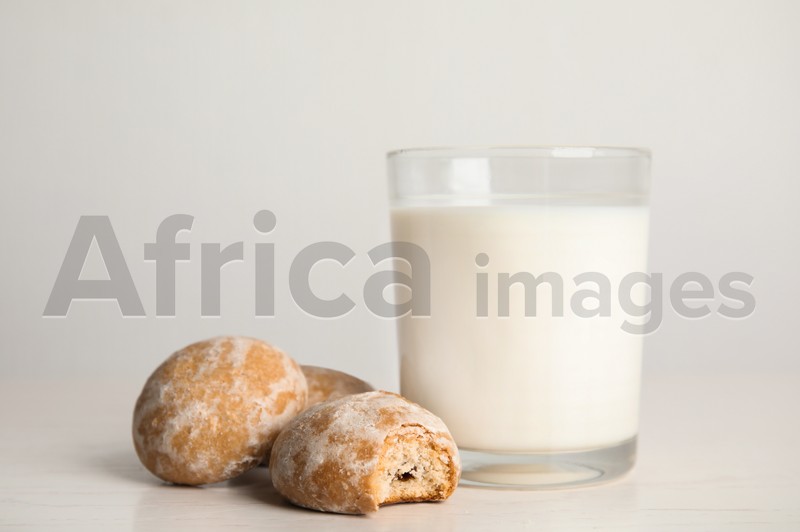 Photo of Tasty homemade gingerbread cookies and glass of milk on white table