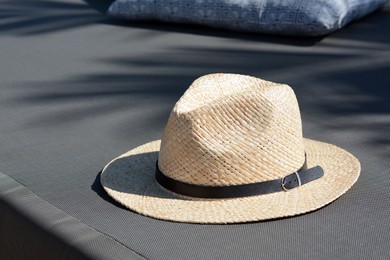 Stylish straw hat and pillow on grey fabric outdoors