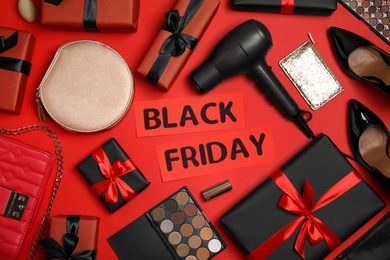 Gift boxes, cosmetics, hairdryer, shoes, women's accessories and phrase Black Friday on red background, flat lay
