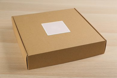 Closed cardboard box on wooden table, closeup