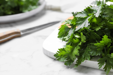 Bunch of fresh green parsley on white marble table, closeup. Space for text