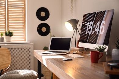 Modern computer and laptop on wooden desk in room. Interior design