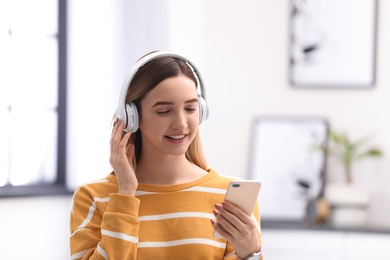 Teenage girl listening to music with headphones against blurred background