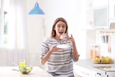 Photo of Woman eating dessert in kitchen. Diet failure