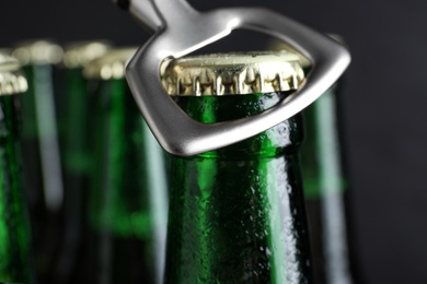 Photo of Opening bottle of beer on dark background, closeup