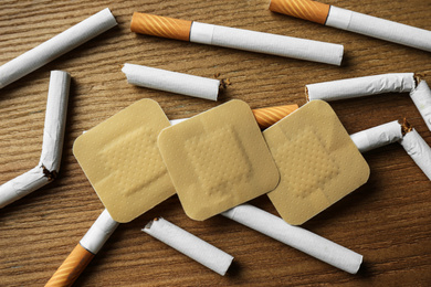 Nicotine patches and cigarettes on wooden table, flat lay