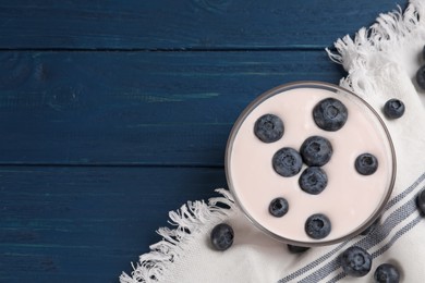 Tasty yogurt served with blueberries on blue wooden table, flat lay. Space for text