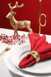 Stylish table setting with red fabric napkin, beautiful decorative ring and festive decor