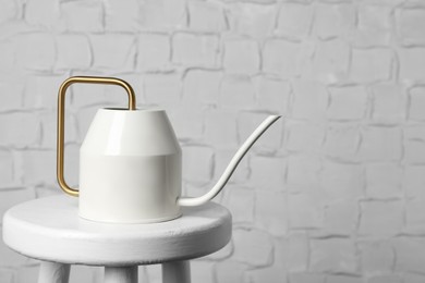 Photo of Ceramic watering can on table against white brick wall, space for text