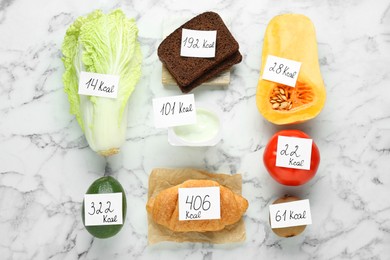 Food products with calorific value tags on white marble table, flat lay. Weight loss concept