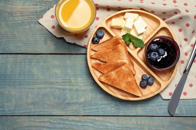 Tasty toasts served with butter and blueberries on light blue wooden table, flat lay. Space for text