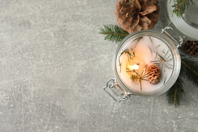 Burning scented conifer candle and Christmas decor on grey table, flat lay. Space for text