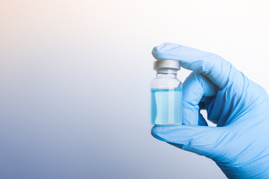 Doctor holding vial with medication on light background, closeup view and space for text. Vaccination and immunization