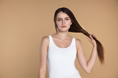 Young woman with strong healthy hair on beige background