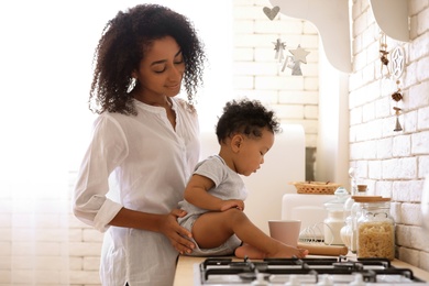 African-American woman with her baby in kitchen. Happiness of motherhood