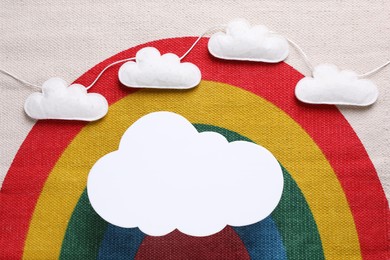 Cloud shaped child's night lamp on fabric with rainbow pattern, flat lay