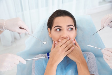 Photo of Young woman scared of dental examination in clinic